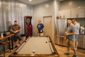 pool table with kitchen and dart board in back
