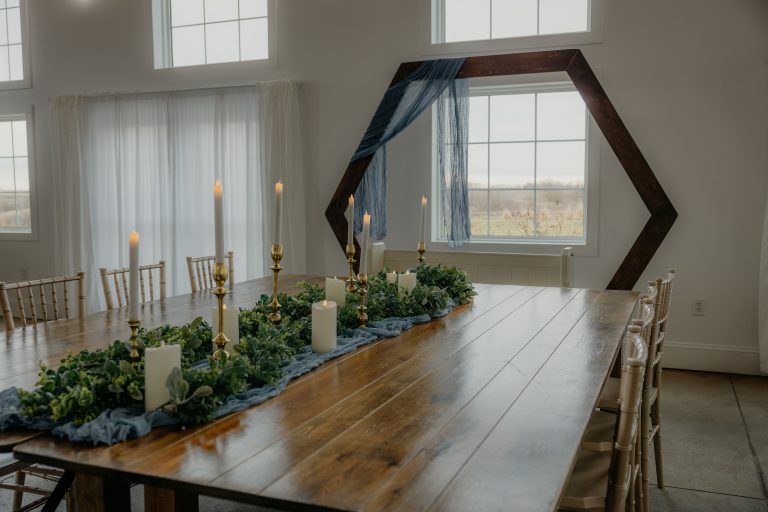 A close-up view of a beautifully decorated wedding head table, featuring elegant place settings, lush floral arrangements, and warm ambient lighting, creating an intimate and inviting atmosphere.